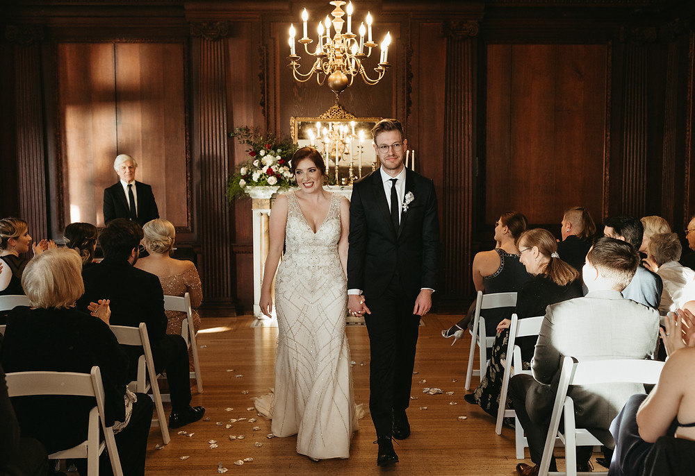 A bride and groom walk down the aisle during their 1920's inspired wedding at the Branford House in Connecticut.
