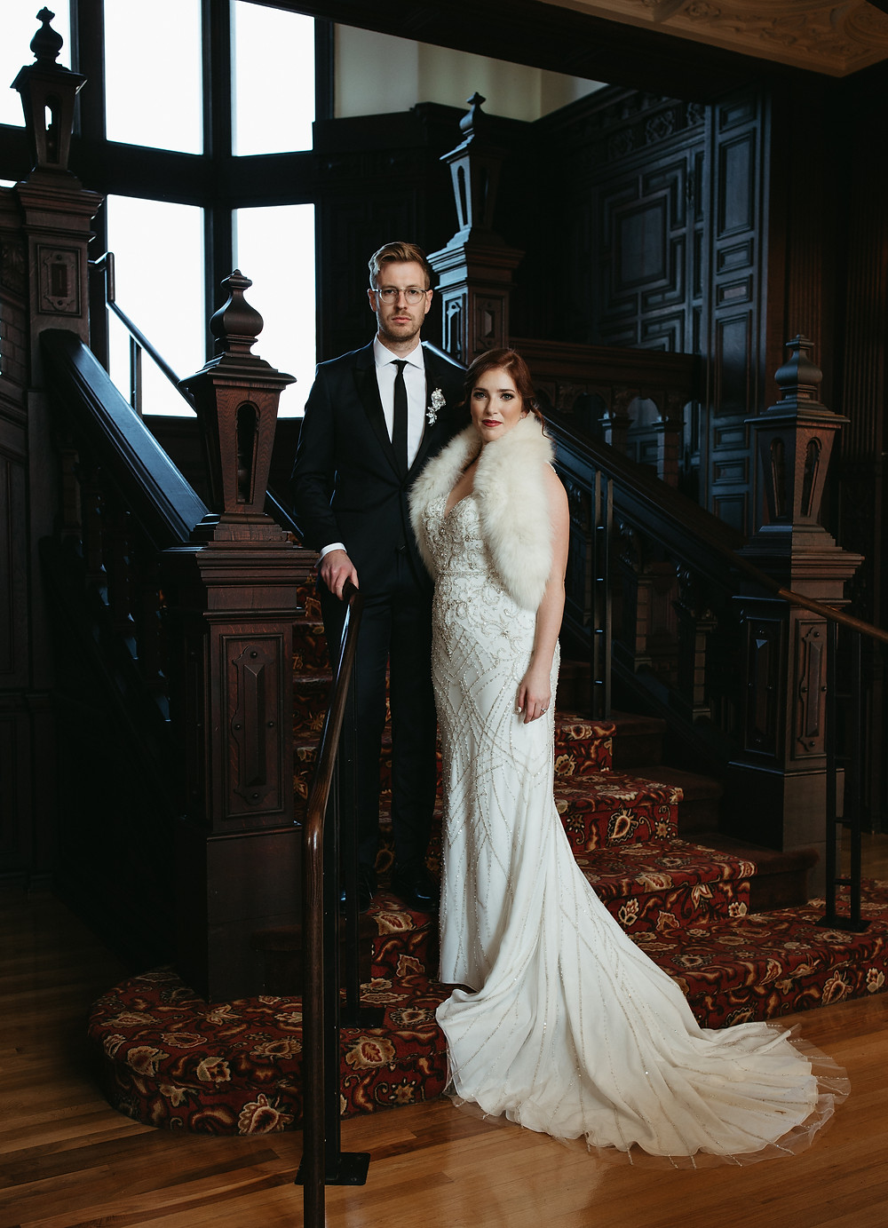 A bride and groom pose on the steps of the Branford House in Connecticut, wearing 1920's inspired attire.