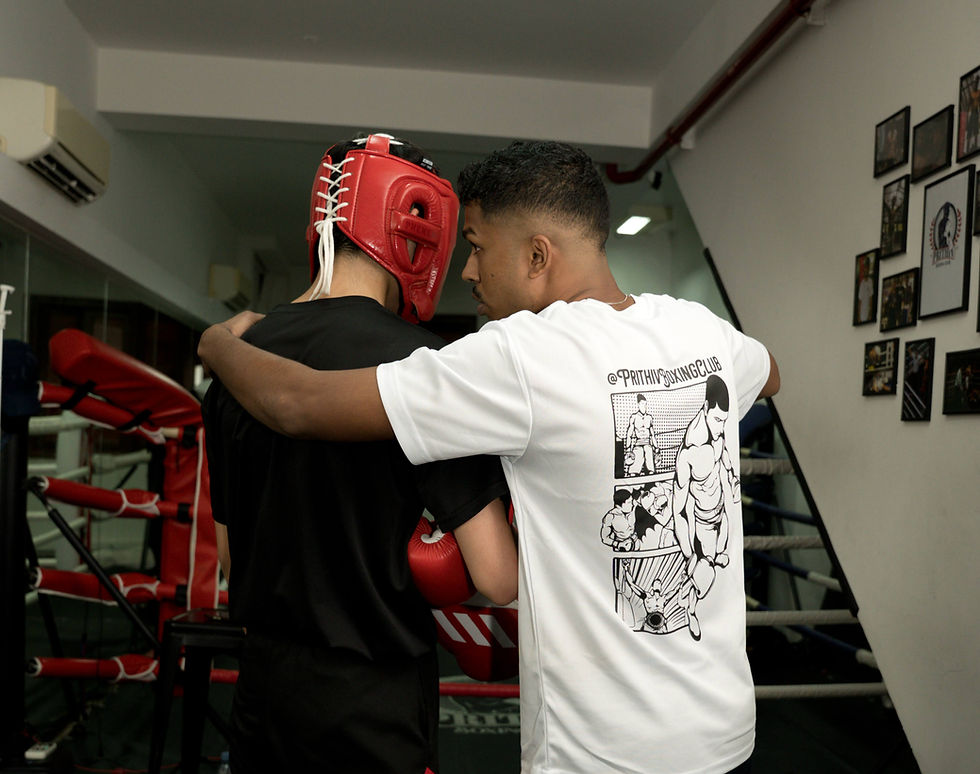Coach giving one-on-one sparring guidance to student wearing headgear at Prithiv Boxing Club Singapore