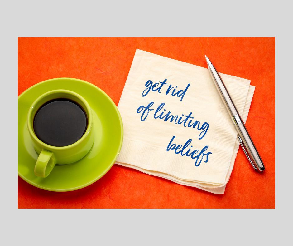 A cup of coffee sitting next to a napkin. Someone has written "Get rid of limiting beliefs" in blue ink on the napkin.