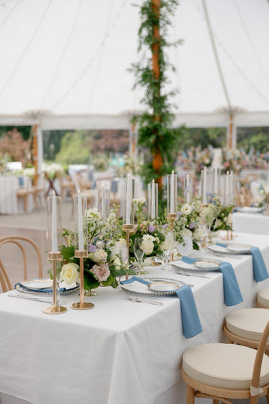 Elegant table setting with floral arrangements and blue napkins at a wedding Giuberti Decor