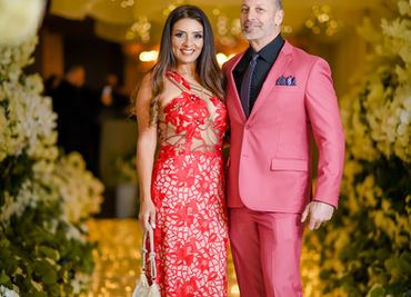 Couple in formal attire, smiling, with floral backdrop and Giuberti Decor