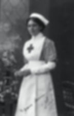 A nurse in a vintage uniform with a red cross stands by a table with flowers. Stained glass window behind. Handwritten text reads "Yours loving."