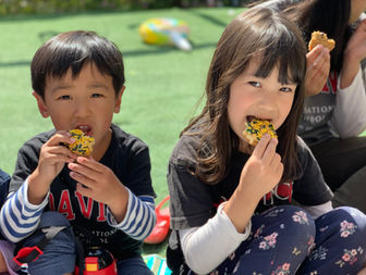 Alumnos de preescolar disfrutan de una merienda juntos durante una actividad al aire libre en Okinawa.