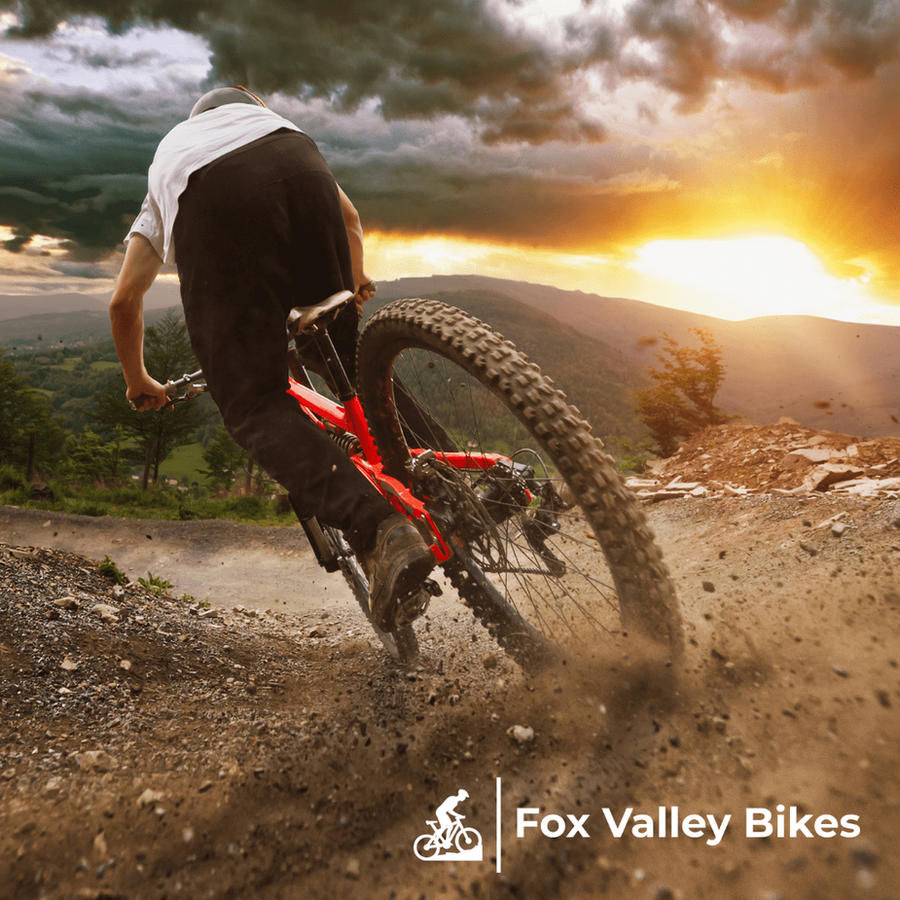 A mountain biker riding a dusty trail at sunset