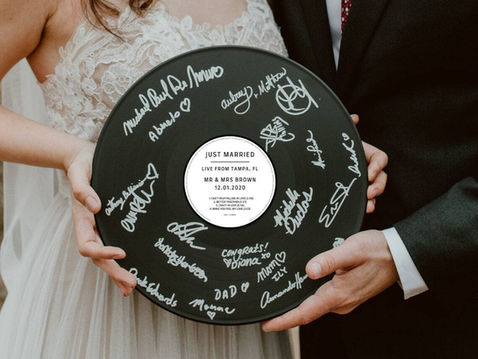 Bride and groom holding a custom playable vinyl record audio guest book filled with handwritten messages from guests – the perfect wedding keepsakes audio video memento for reliving wedding moments years later.
