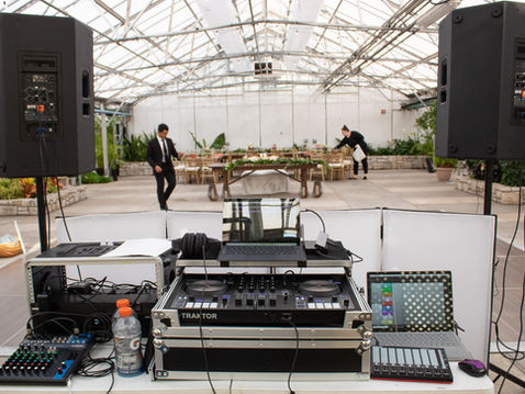 Wedding DJ equipment redundancy in action: professional setup with backup Traktor controller, Yamaha mixer, dual laptops, and battery-powered speakers for uninterrupted ceremony and reception sound