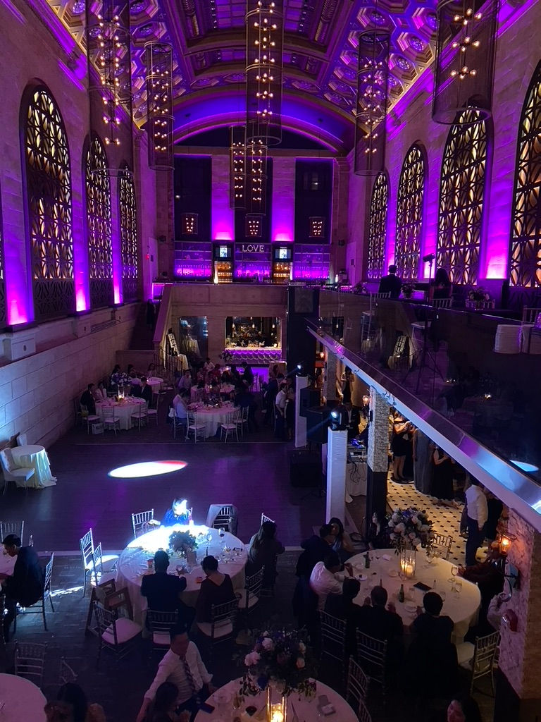 Luxury wedding lighting design with strategic purple uplighting accentuating high arched windows, ornate ceilings, and architectural details in a grand ballroom venue