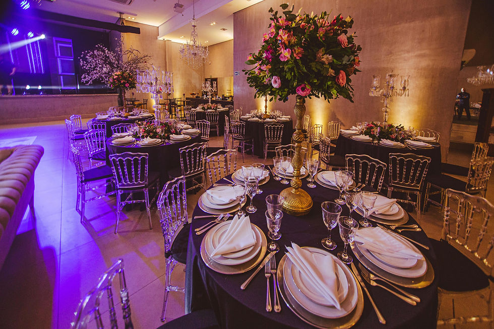 A sophisticated wedding reception with black table linens and tall floral centerpieces under warm architectural lighting.