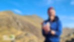 A mountain guide holding various snacks with Yr Wyddfa (Snowdon) in the background