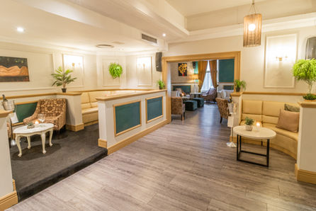 The welcoming interior of the Rabbit Hole venue, showing a split-level lounge area with a mix of cream-colored couches and patterned armchairs, and warm lighting that highlights the cozy atmosphere.
