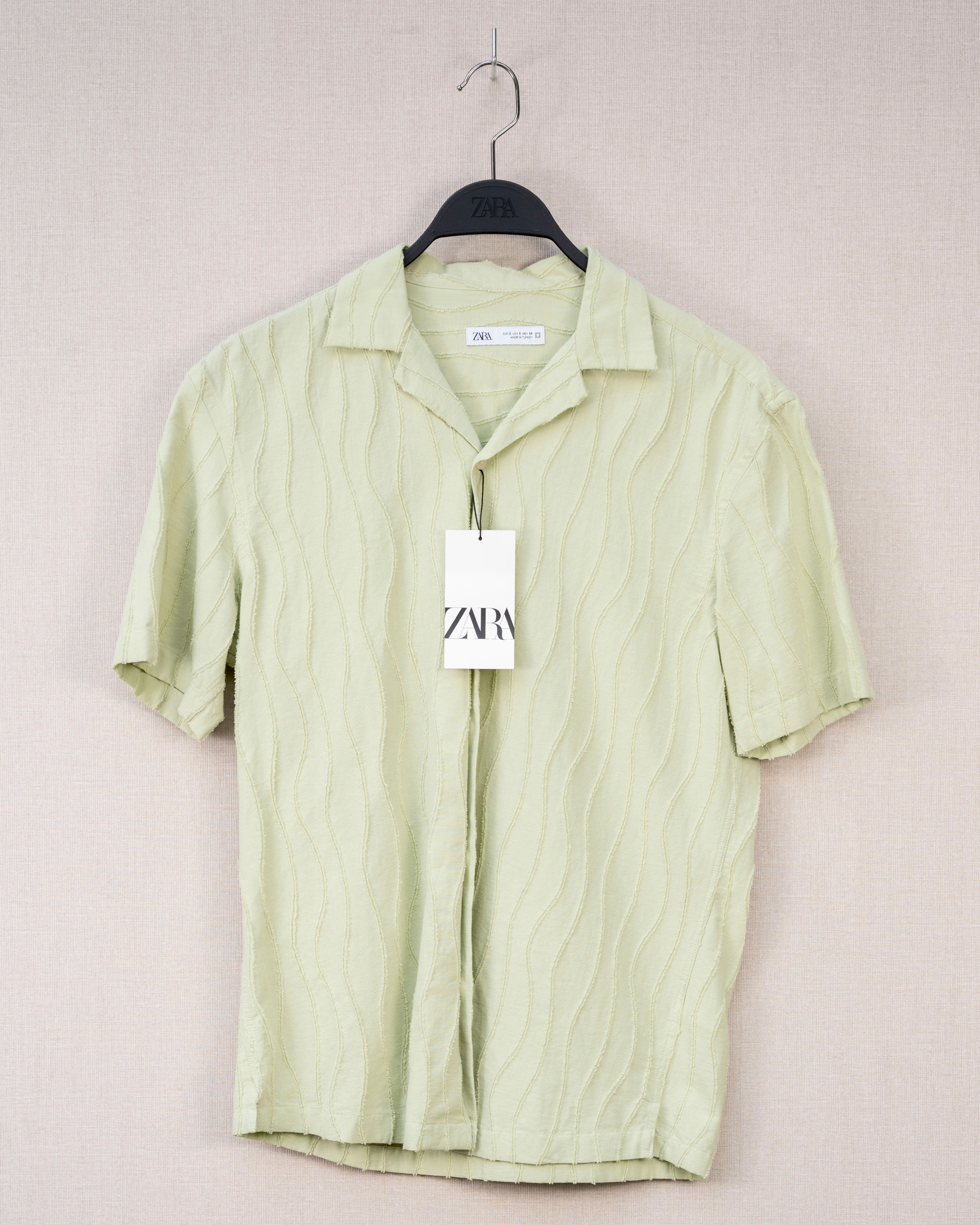 A LIGHT GREEN COLOURED SHORT-SLEEVE BUTTON-UP SHIRT