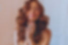 Red-haired woman with flower accessories in curled hair, delightfully clasping hands and smiling with eyes closed