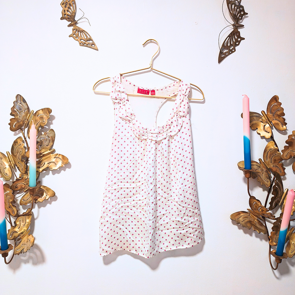 Thumbnail: White and pink polka dot top on a hanger near wall decor.