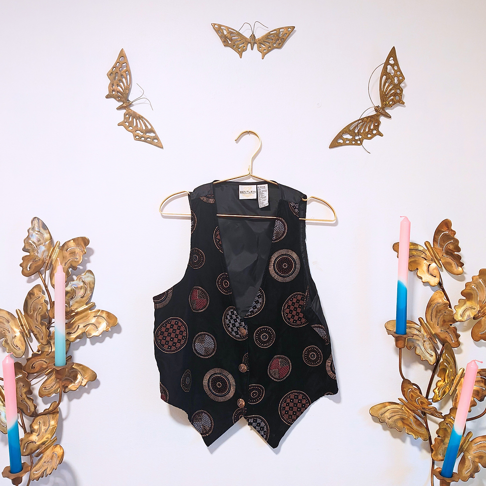 Thumbnail: Black vest with circle designs, hanging on a hanger, against a white wall.