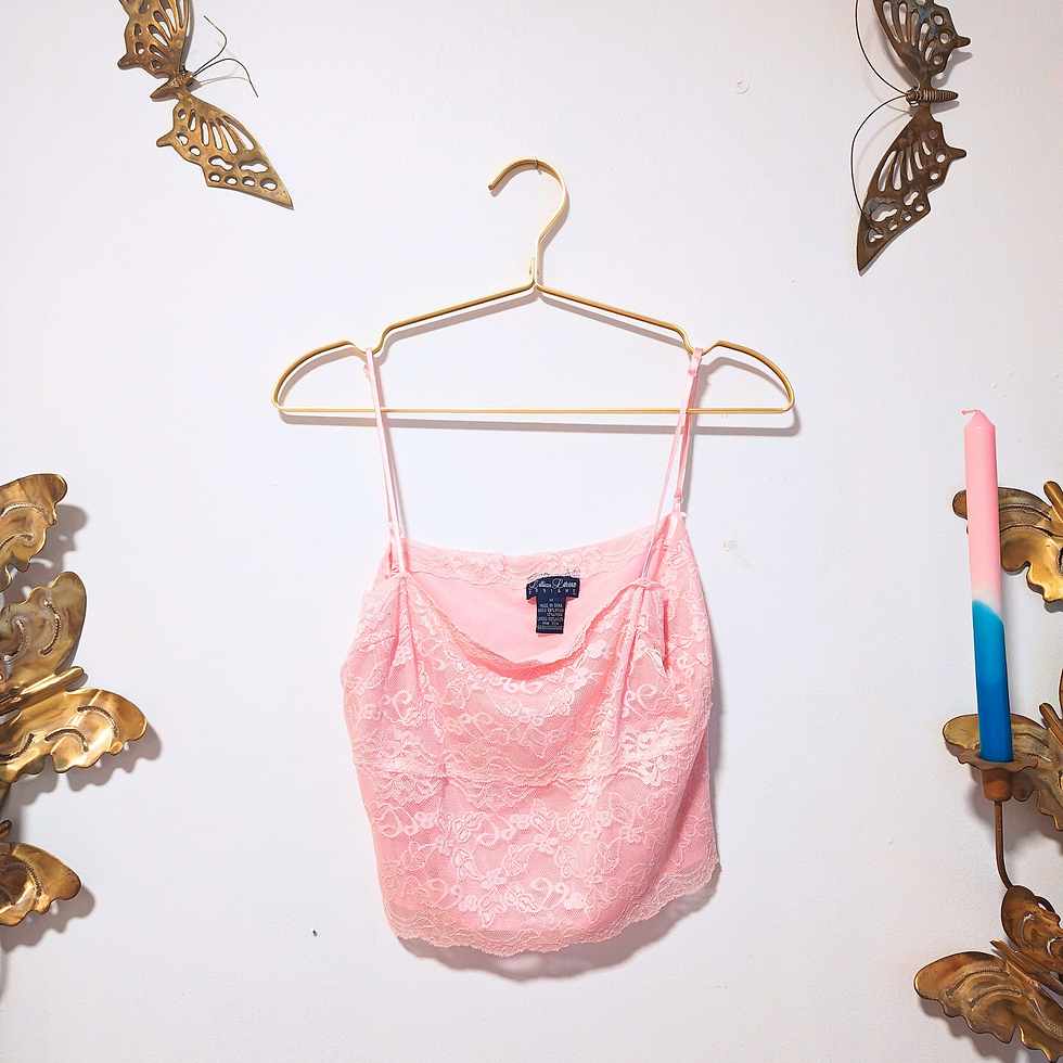 Thumbnail: Pink top hanging on a gold hanger against a white wall background.