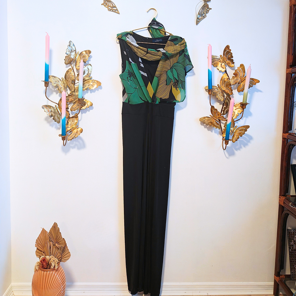 Thumbnail: Elegant black jumpsuit and green floral top hanging on a white wall.