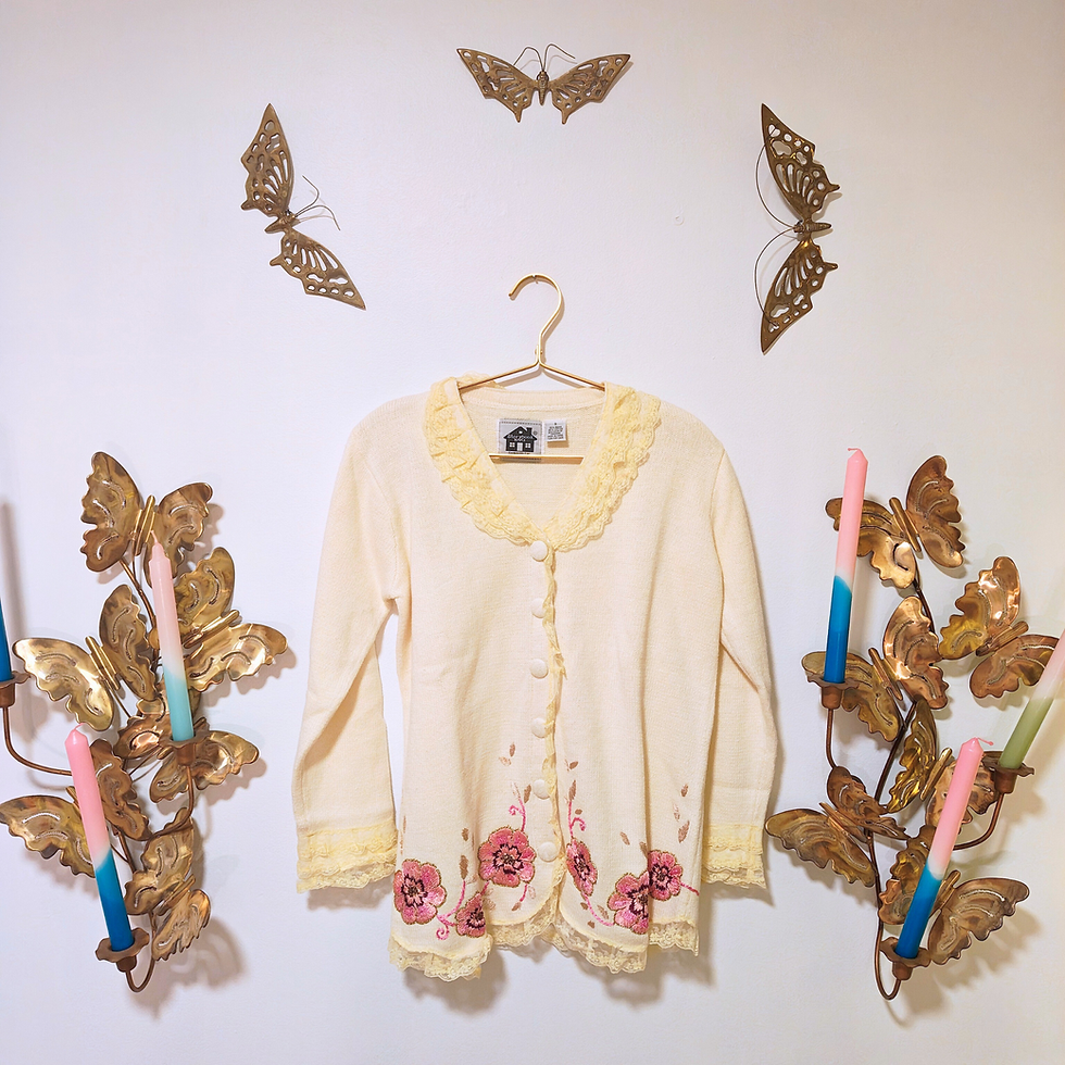 Thumbnail: Cream sweater with floral details hanging on the wall with butterfly decor.