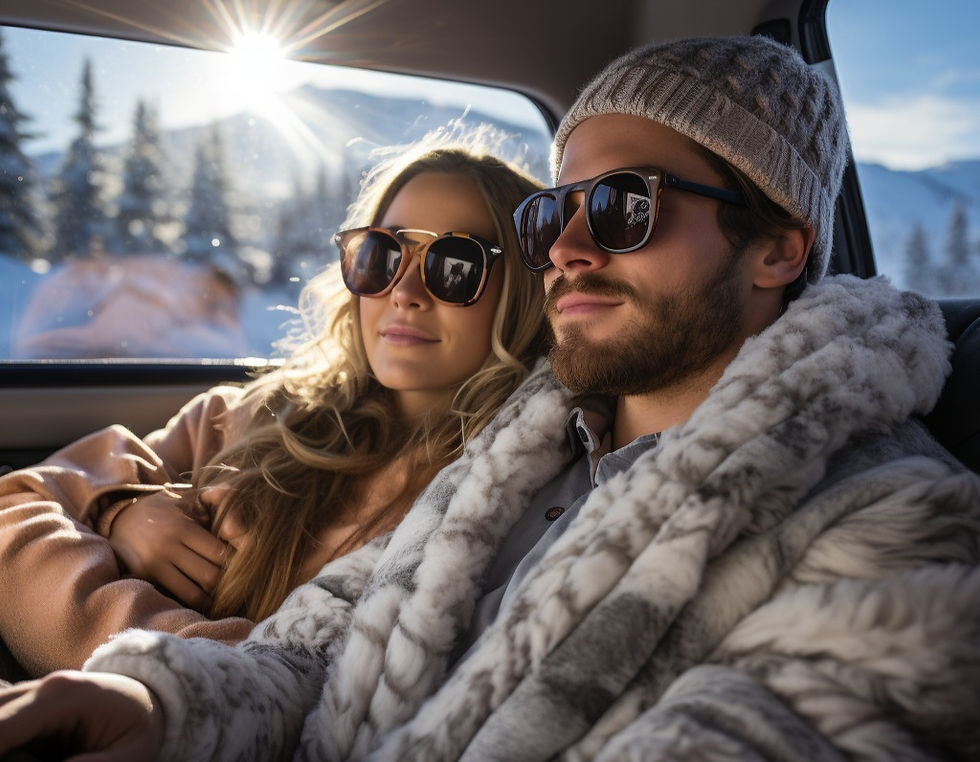 a happy young couple in warm winter clothes and sunglasses riding in the back of a car through a sunny mountain road