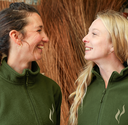 Sophia Campbell‑Shaw and Abi Griffin smiling in willow workshop, founders of Woven Farewell Coffins