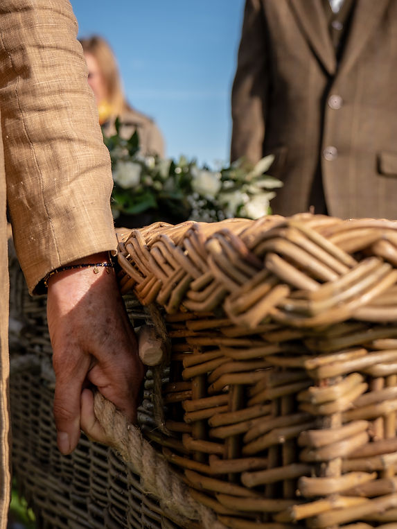 Close‑up of hands on a woven willow coffin, supporting quote “Every goodbye is deeply personal”
