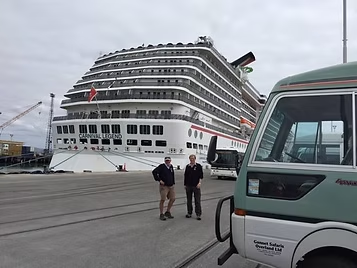 Andy Neilson standing by a Gannet Safaris bus at a docked cruise ship in Napier Port.
