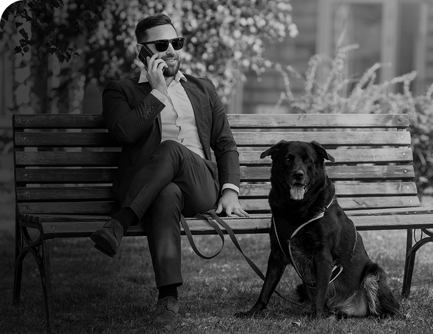 Confident businessman in a suit talking on phone while sitting on a park bench – trusted local insurance concierge services a