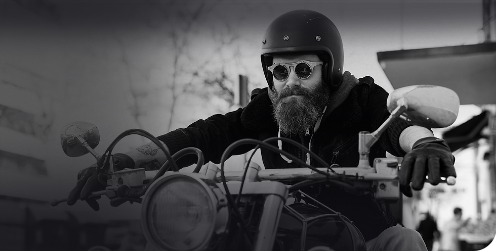 Bearded man riding a motorcycle with protective gear – motorcycle and auto insurance for adventurous lifestyles.