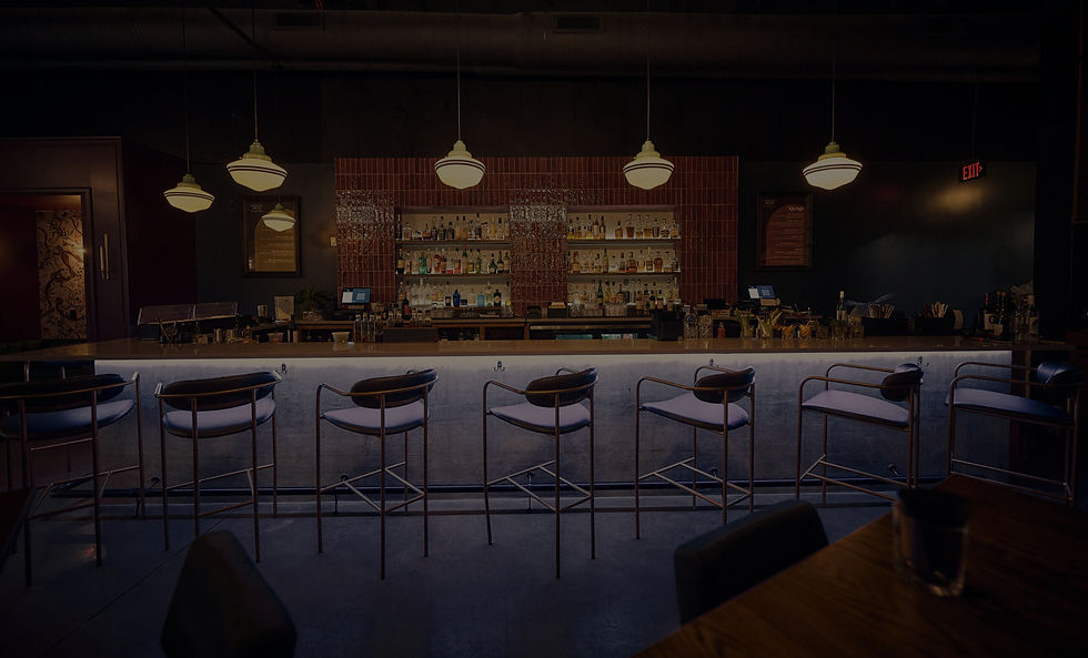 Dimly lit bar with empty stools and hanging lights