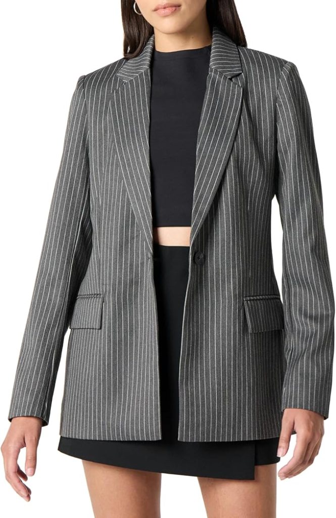 A woman wearing a gray pinstripe blazer over a black top, styled with a sleek, modern look.