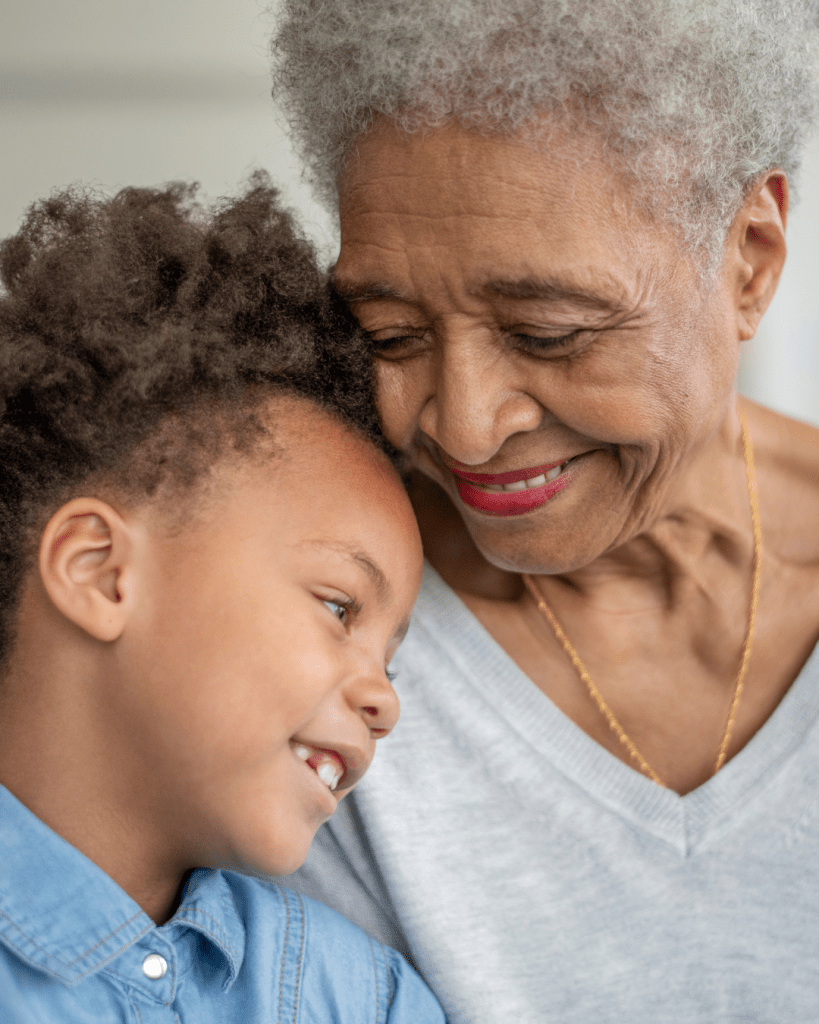 A joyful grandmother and a young child sharing a loving moment, smiling close together.
