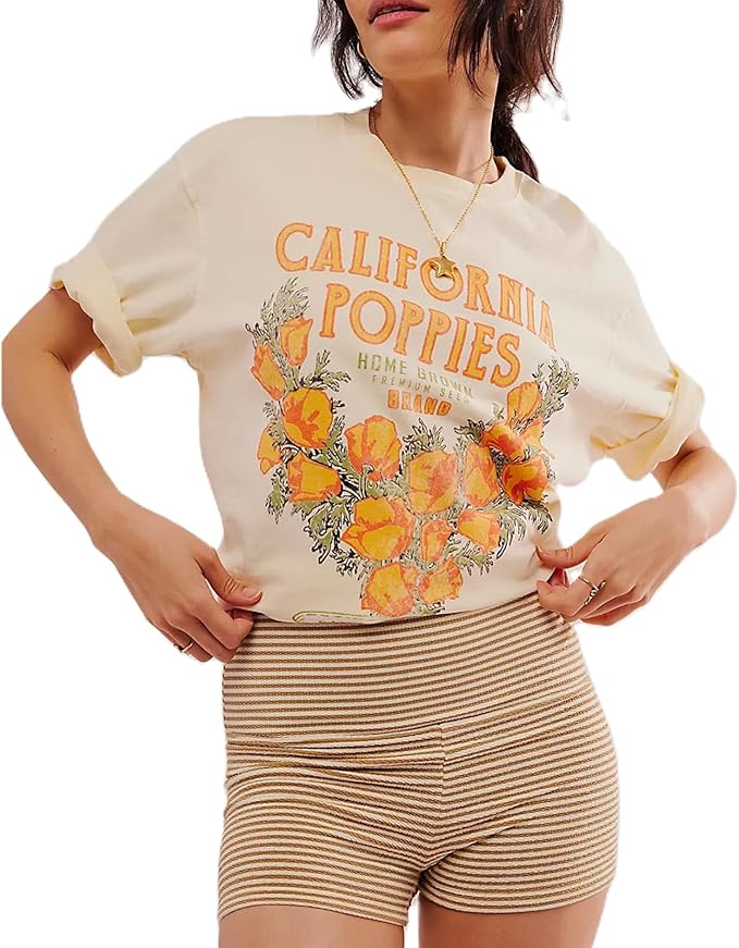 A young woman wearing a beige graphic tee with 'California Poppies' printed on it, paired with striped shorts, demonstrating a casual summer outfit.