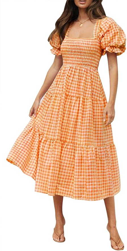 A woman wearing a summery orange gingham dress with puff sleeves and a tiered skirt, standing in a casual pose.