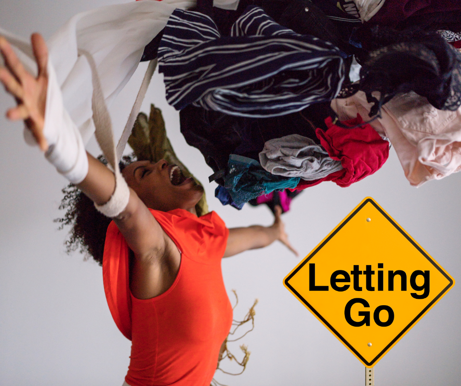 A person in a bright orange outfit passionately throws an assortment of colorful clothing items into the air, with a sign reading 'Letting Go' visible in the image.