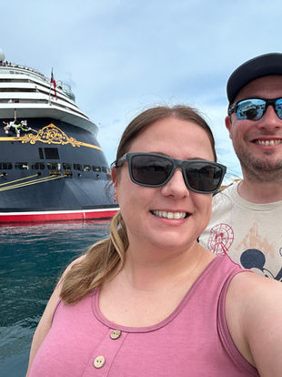 Dani and Paul standing in front of the back of the Disney Magic cruise ship