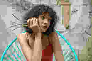 Woman wearing red tank top holding 4 reusable metal straws