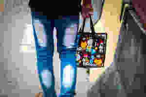 back shot of person wearing faded jeans holding a reusable polyethylene bag