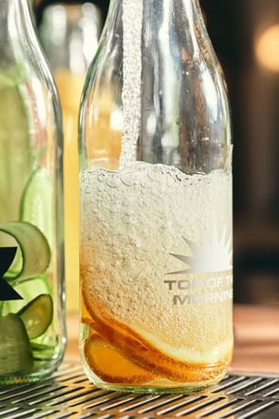 Sparkling drink being filled in bottle with orange slices