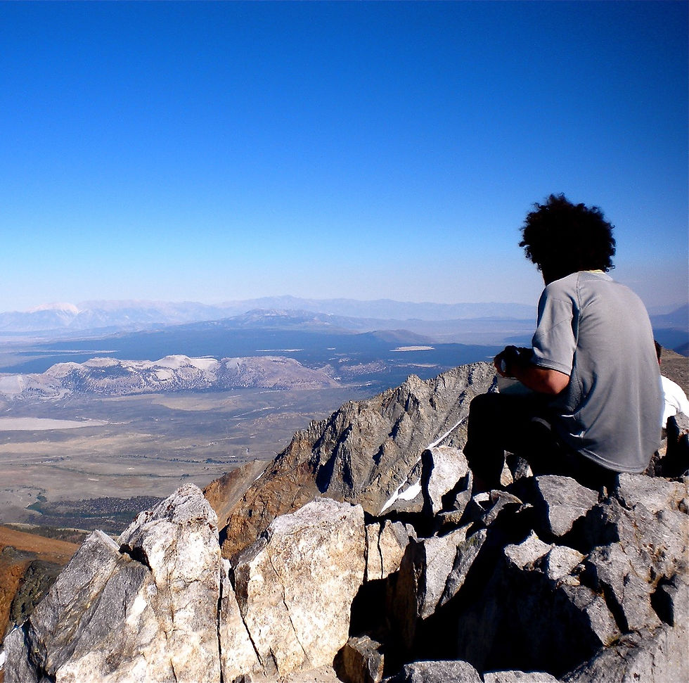 A hiker resting on the summit of Dana Peak, high above the owens river valley