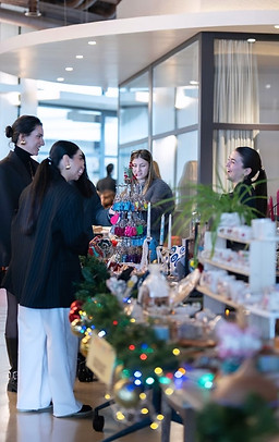 Alışveriş yapanlar, el yapımı ürünler ve Noel ışıkları ile dolu bir pazar standı