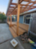 Wooden deck with pergola attached to a blue house
