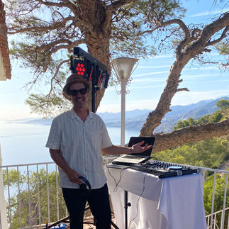 DJ Leo tritt hinter dem DJ-Pult am Mirador Cerro Gordo an der Costa Tropical während einer Boda mit Meerblick und goldenem Licht auf