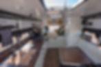 Custom skoolie interior with a full kitchen, dark wood countertops, black high-arch faucet, and a compact stove. A cozy sleeping area with green bedding and overhead storage is visible in the background. A Marshall speaker sits on the windowsill, adding a stylish touch to the modern bus conversion.
