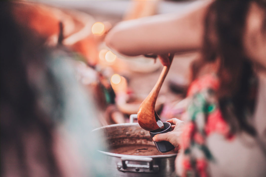A woman pours cocoa from a pot into a glass
