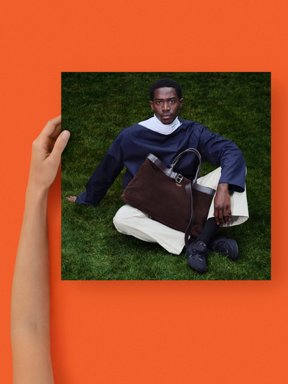 Damson Idris sitting on a green plush rug, wearing head to toe Prada