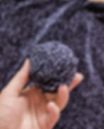 Woman's hand holding a ball of dark blue chenille yarn