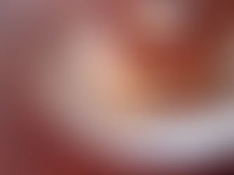 A stack of four waffles on a white plate covered in syrup with a pat of butter on the top