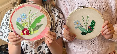 Two children proudly hold up their wildflower posy embroideries