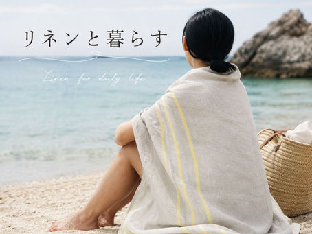 ビーチでリネンのバスタオルを羽織って座っている女性