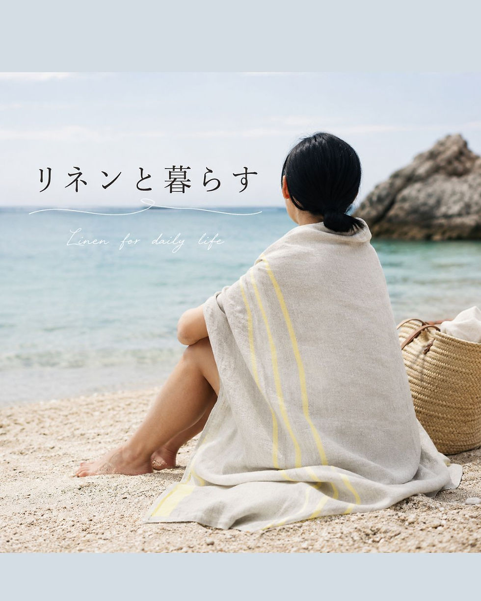 ビーチでリネンのバスタオルを羽織って座っている女性